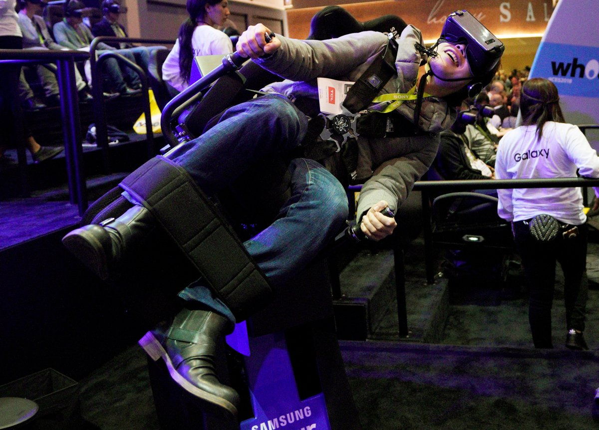  A CES show goer tries out the Flying Dino ride using a Samsung VR headset. 